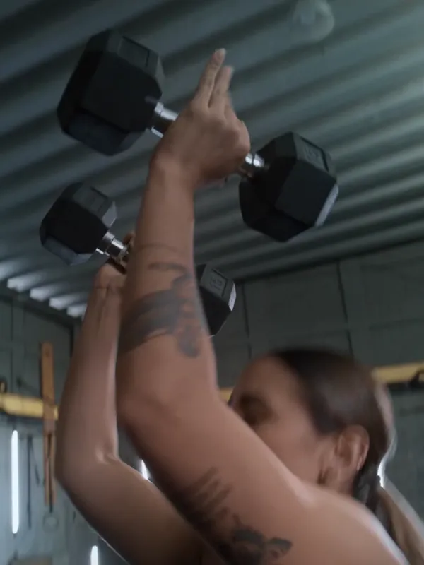 A woman pressing dumbbells overhead