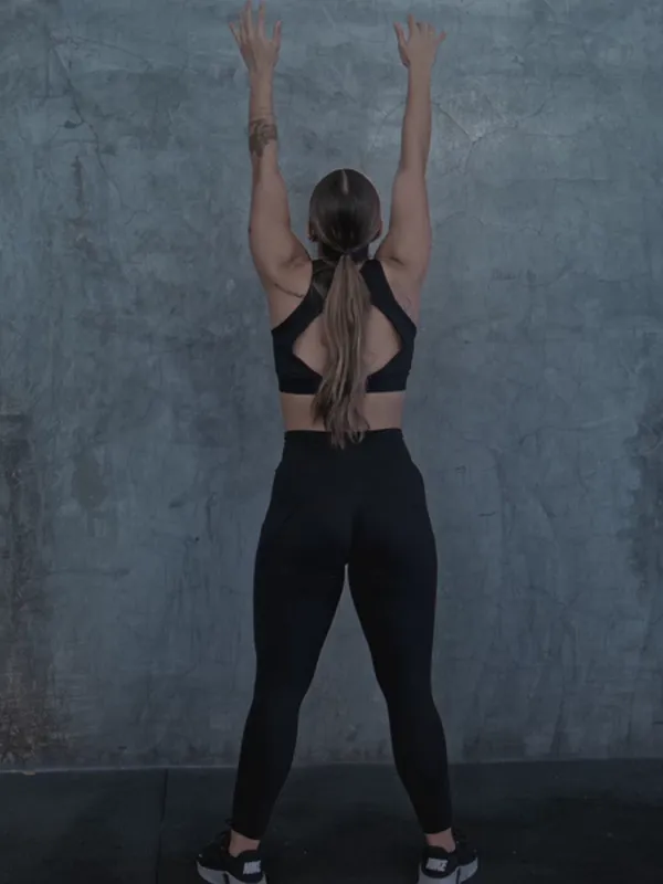 A woman in leggings training with a medicine ball, seen from behind